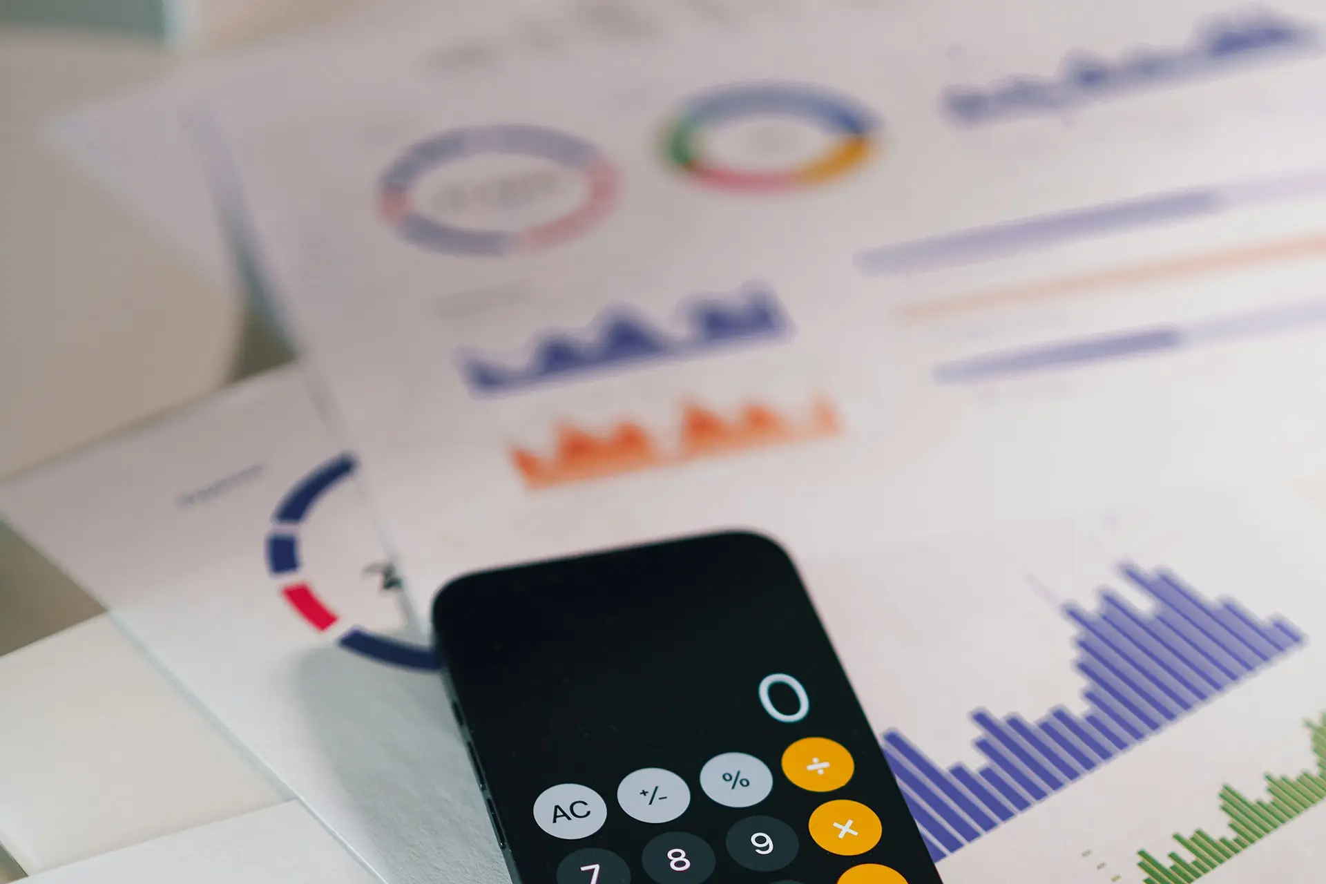 Smartphone mit Taschenrechner auf Ausdrucken mit Diagrammen