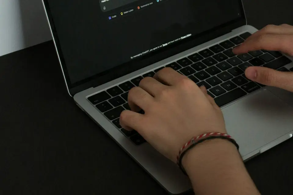 Hände tippen auf der Tastatur eines Laptops mit geöffnetem Chatfenster