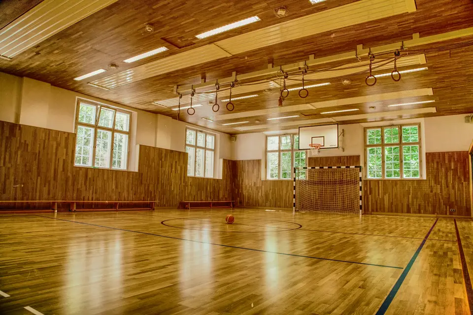 Holzparkettboden einer Turnhalle vor einer weißen Wand
