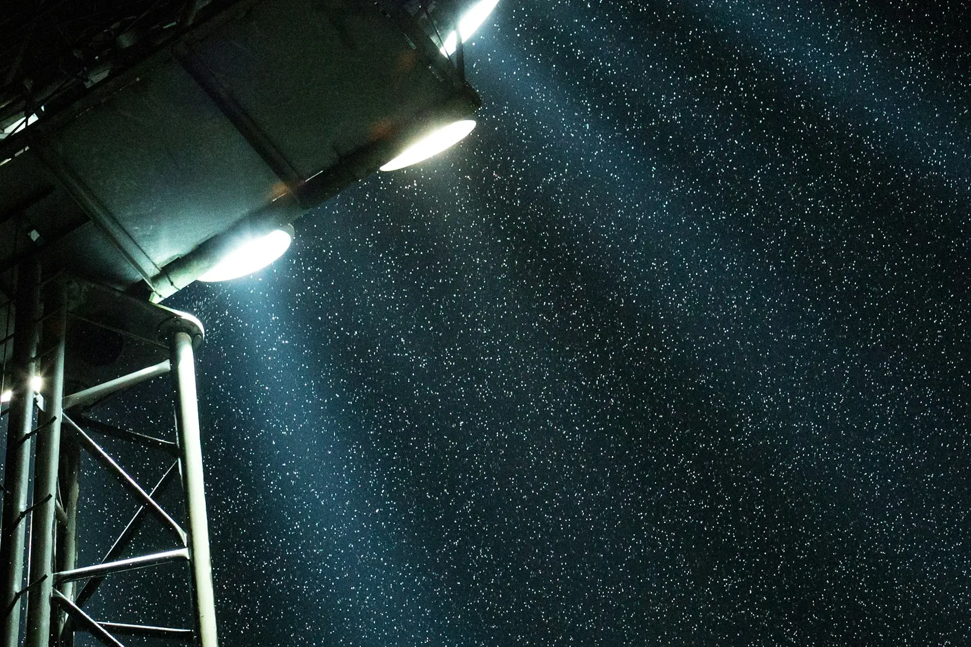 Flutlicht eines Sportplatzes beleuchtet fallenden Schnee am Abend
