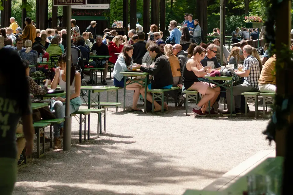 Menschen sitzen auf Stühlen im Grünen unter Bäumen