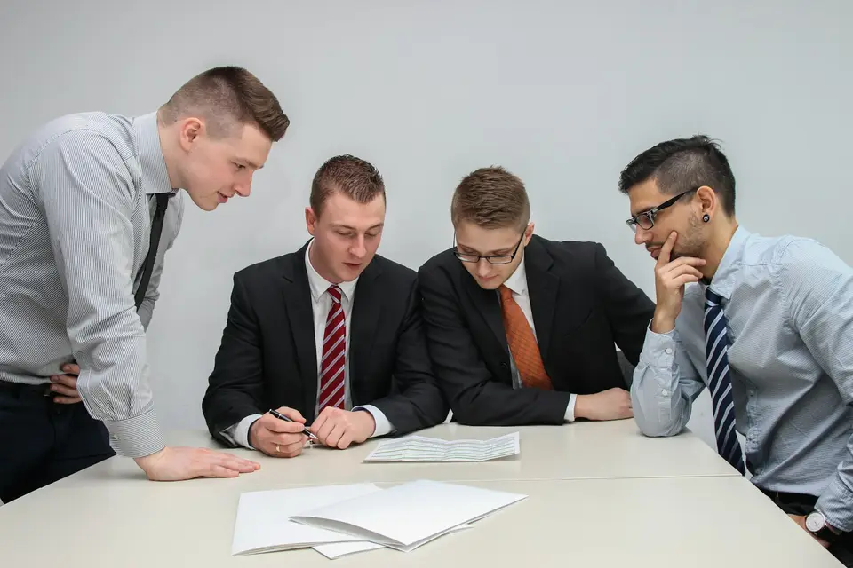 Vier Männer beugen sich über Unterlagen auf einem Besprechungstisch