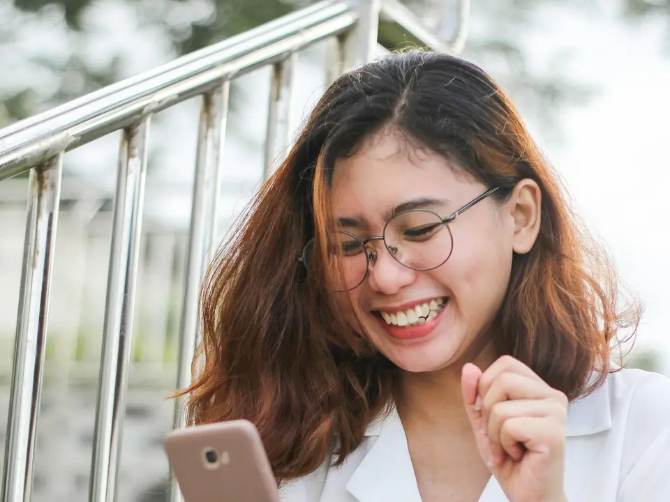 A smiling woman checking her smartphone.