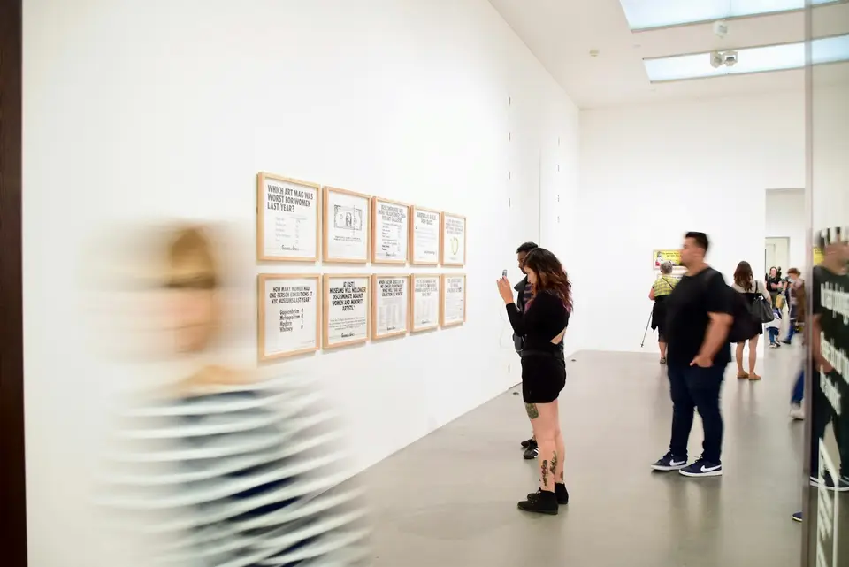 Visitors walking through a bright contemporary art gallery.