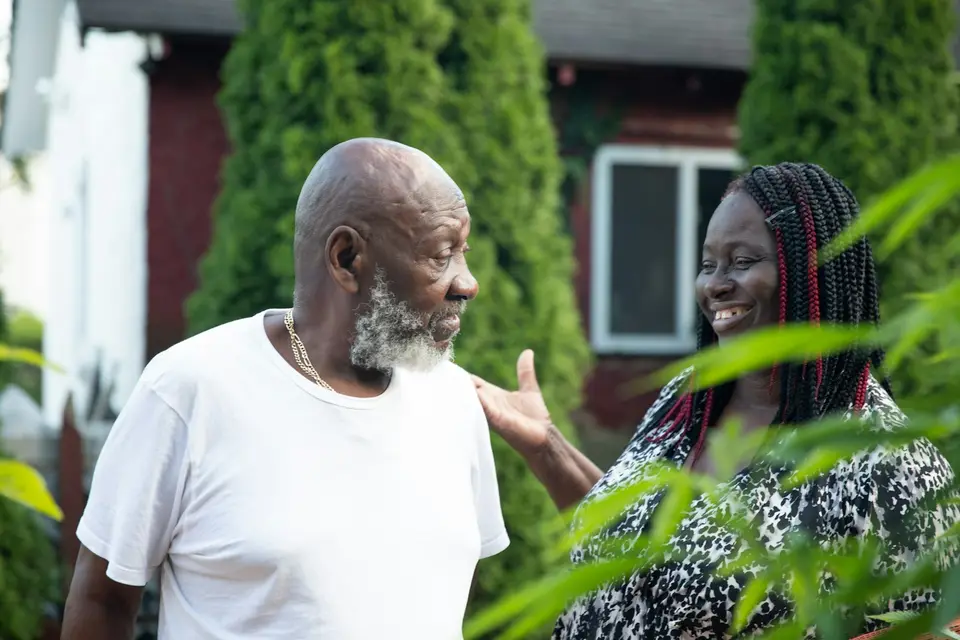 Two neighbors talking outside their homes.