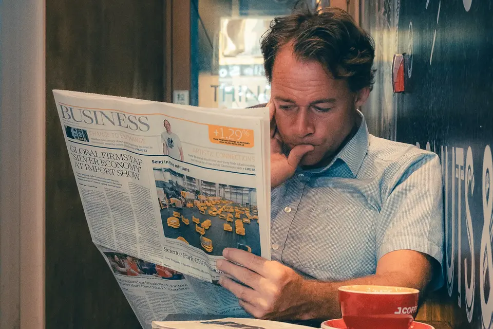 Ein Mann liest in einem Café aufmerksam eine Zeitung