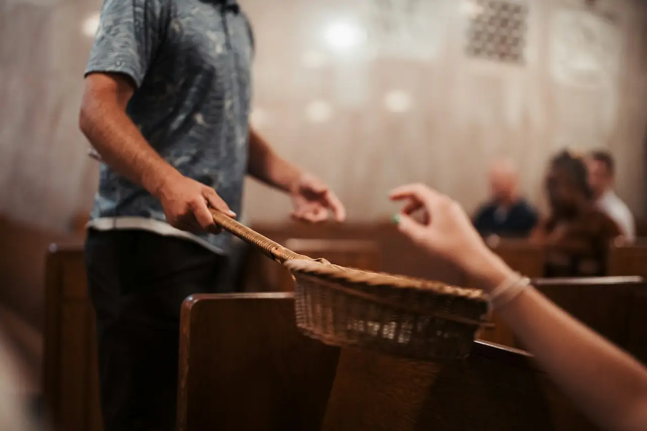 An offering basket being passed along a row during a service.