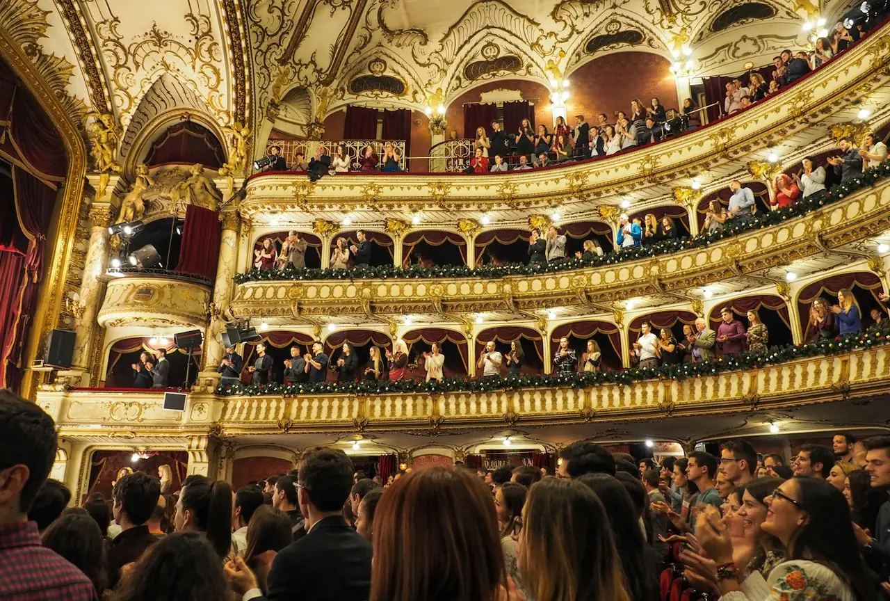 An audience filling the seats and balconies of an ornate theater.