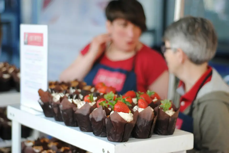 Two volunteers in aprons running a baked goods stand.