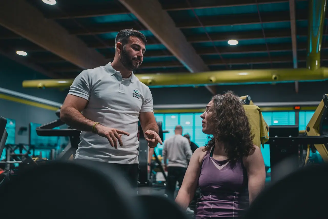 Ein Trainer berät eine Kundin im Fitnessstudio.