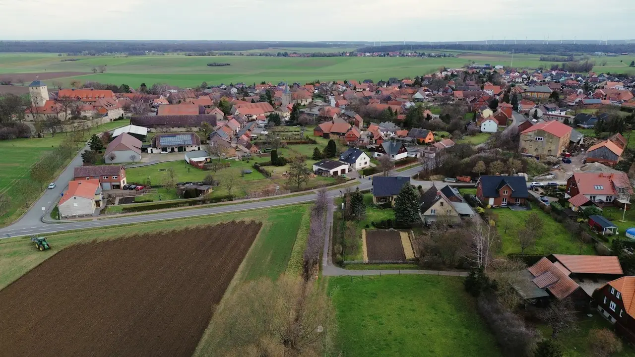 Ein Dorf liegt von oben gesehen zwischen Feldern.