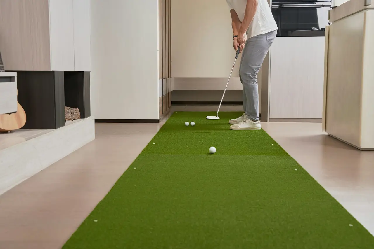 Eine Person übt in einem hellen Raum auf einer Putting-Matte.
