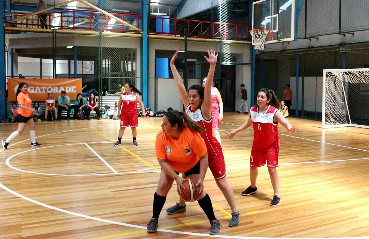 Spielerinnen trainieren in einer Sporthalle mit Handball und Tor.