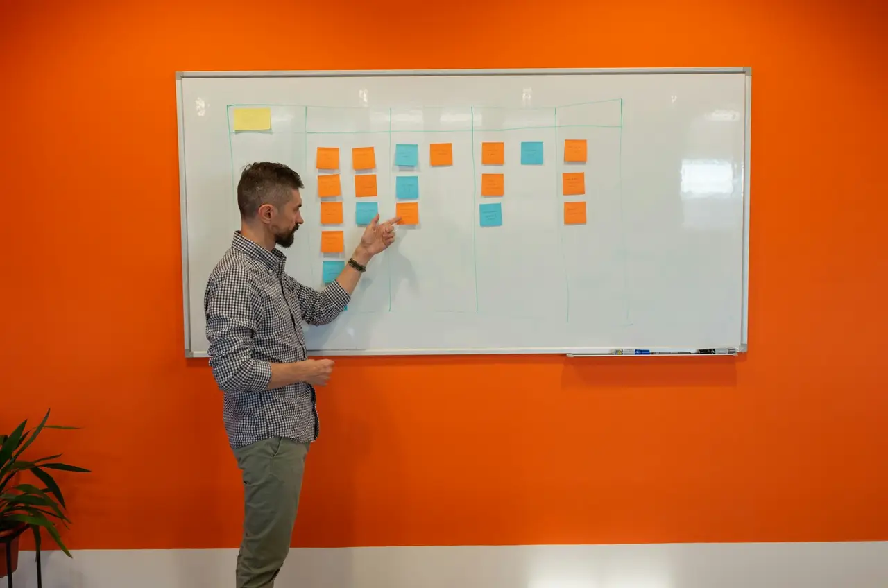 Ein Mann ordnet an einem Whiteboard farbige Notizzettel.