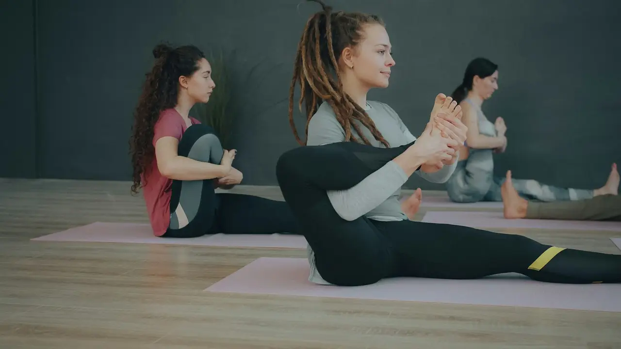 Drei Frauen üben auf Matten in einem Kurs.
