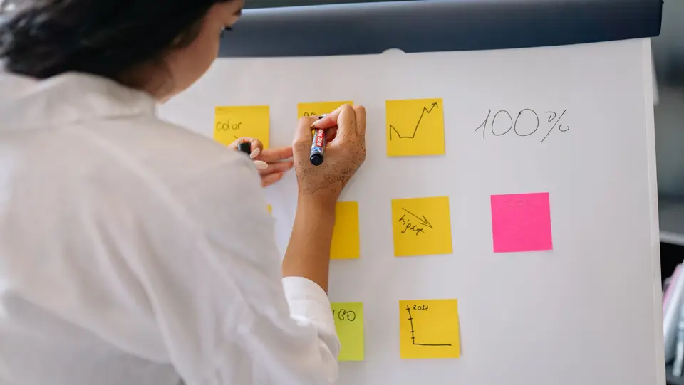 A person organizing notes and charts on a wall.