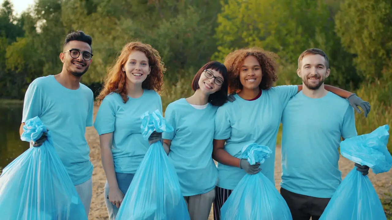 Fünf Freiwillige in blauen Shirts stehen lachend beisammen.