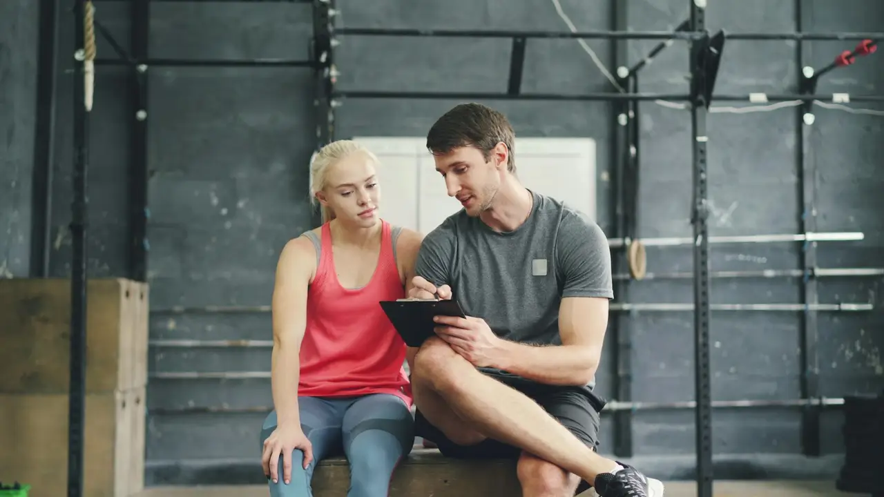 Ein Coach bespricht mit einer Athletin Werte auf dem Tablet.