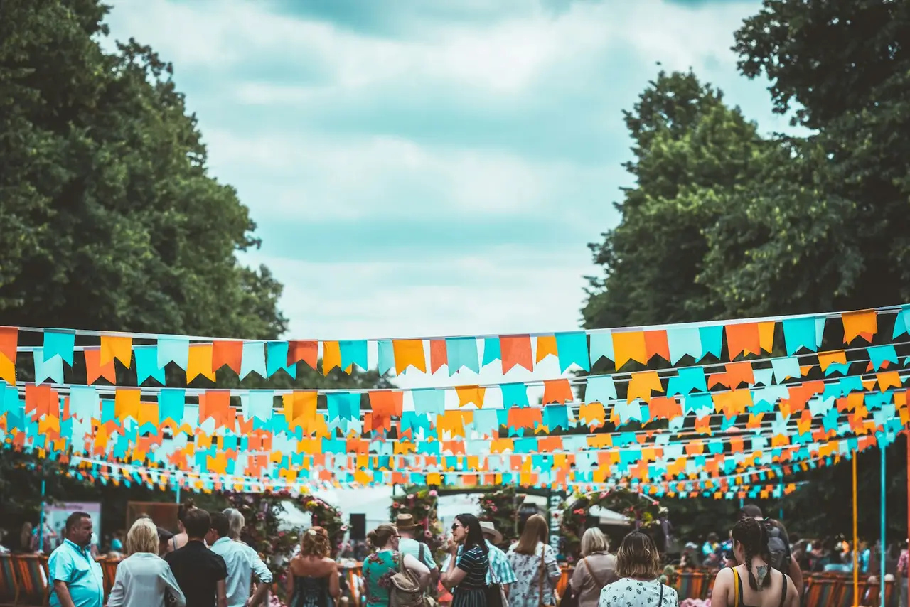 Bunte Wimpelketten hängen über einem Fest im Freien.