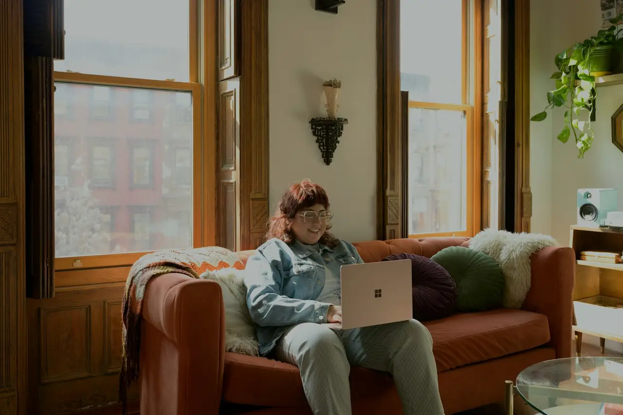 Eine Person sitzt mit dem Laptop auf dem Sofa.