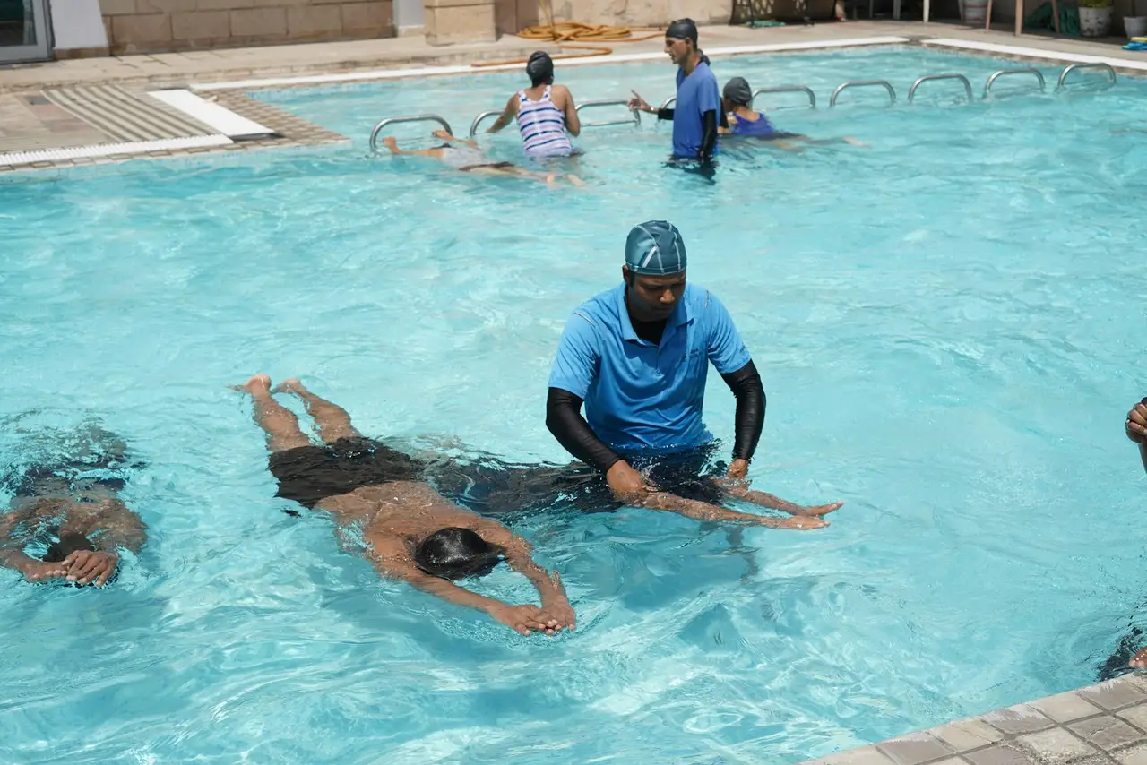 Ein Schwimmlehrer unterstützt ein Kind im Wasser.
