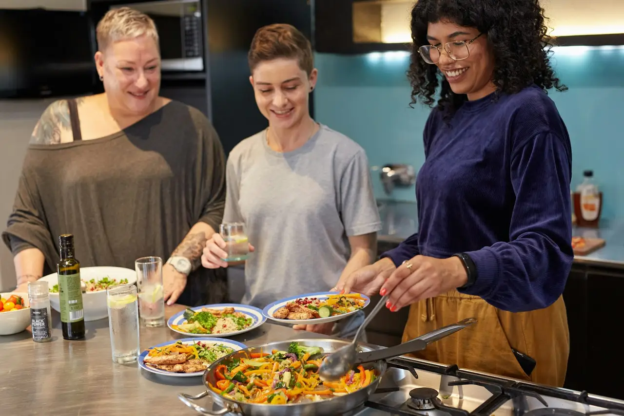 Drei Frauen kochen gemeinsam in einer Lehrküche.