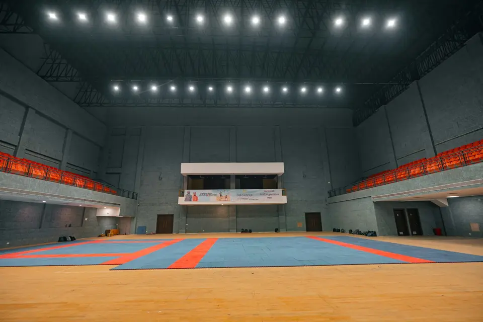 Eine leere Sporthalle mit Spielfeldmarkierungen und Tribünen.