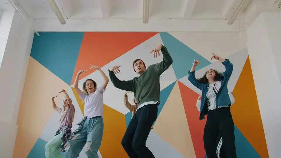 Eine Gruppe übt eine Choreografie vor einer bunten Wand.