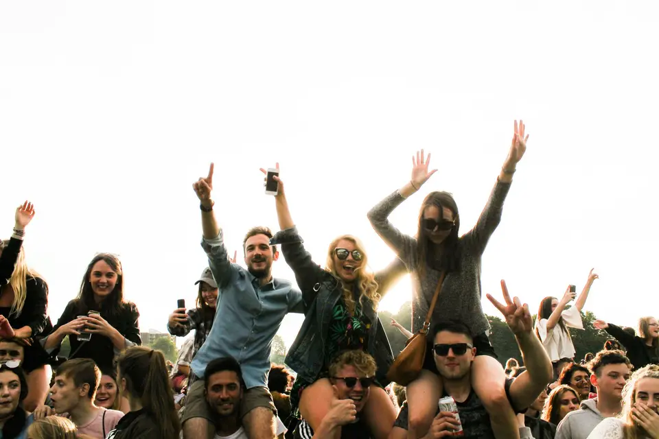 Freunde feiern mit erhobenen Armen im Gegenlicht.