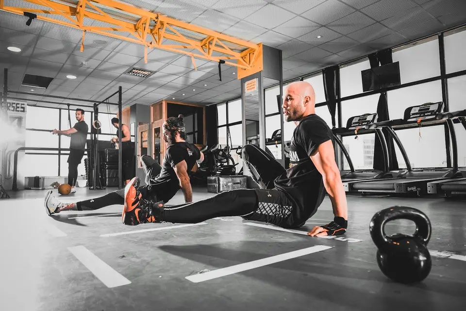Athleten dehnen sich in einer Box neben einer Kettlebell.