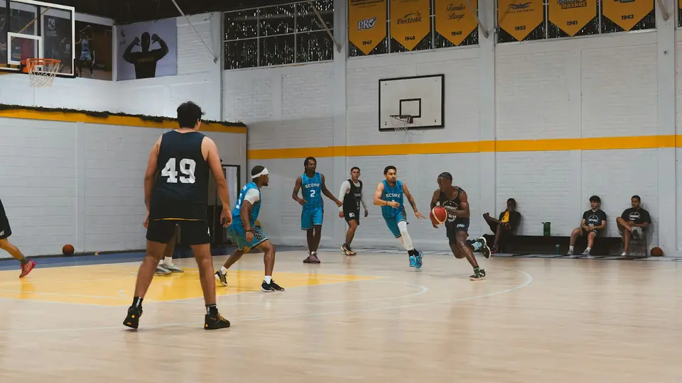 Ein Team spielt in einer Schulsporthalle Basketball.