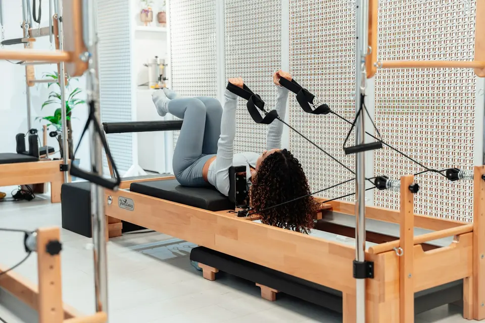 Eine Frau trainiert mit Schlaufen am Reformer.