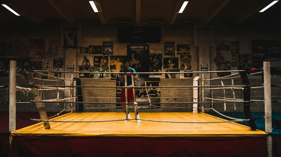 Ein Boxring steht in einem alten Gym voller Plakate.