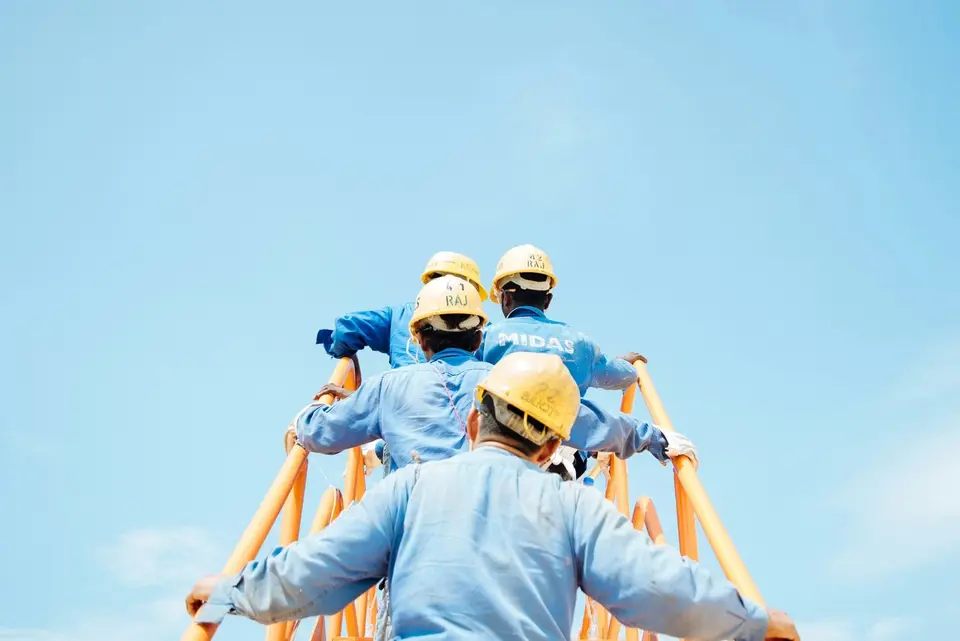 Arbeiter auf Brücke vor blauem Himmel