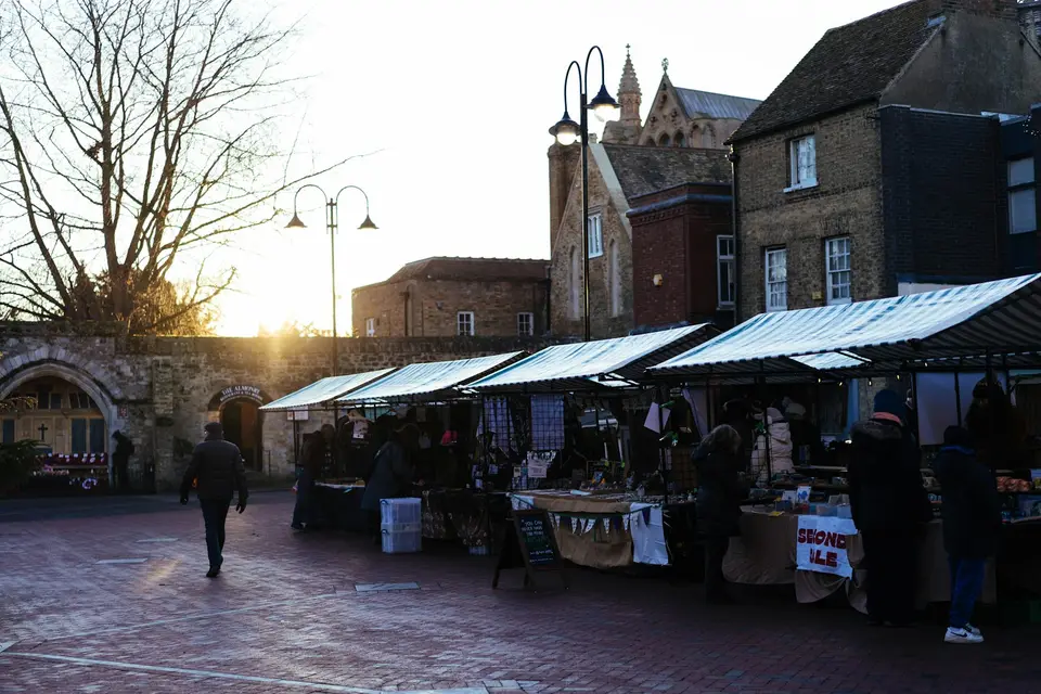 Stände eines Wochenmarkts stehen in der Abendsonne.