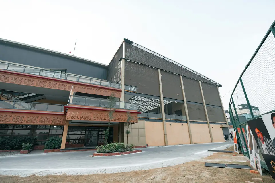 Eine moderne Sporthalle steht an einer Zufahrt.