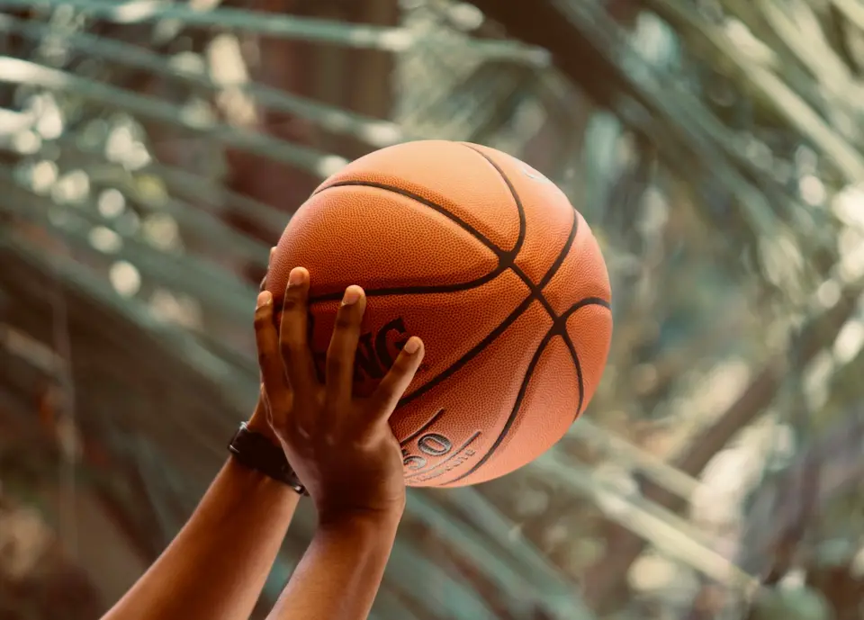 Eine Hand wirft einen Basketball in die Luft.