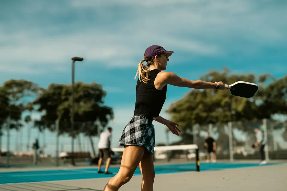 A woman hitting a shot during an outdoor pickleball game.