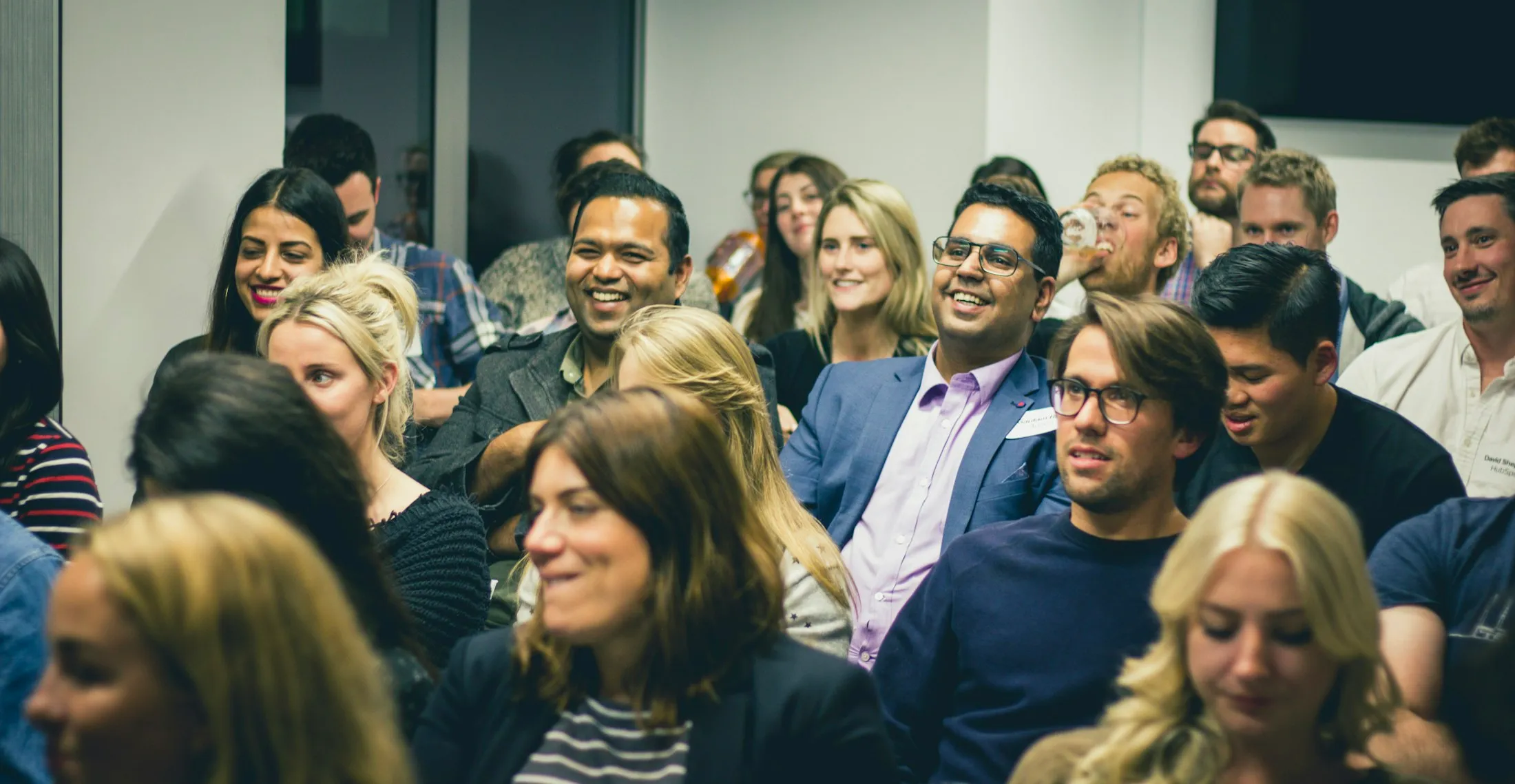 Professionals smiling and listening during a conference session.