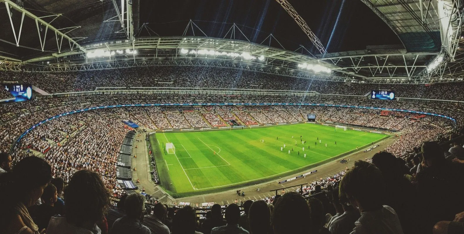 Ein voll besetztes Fußballstadion während eines Spiels unter Flutlicht.
