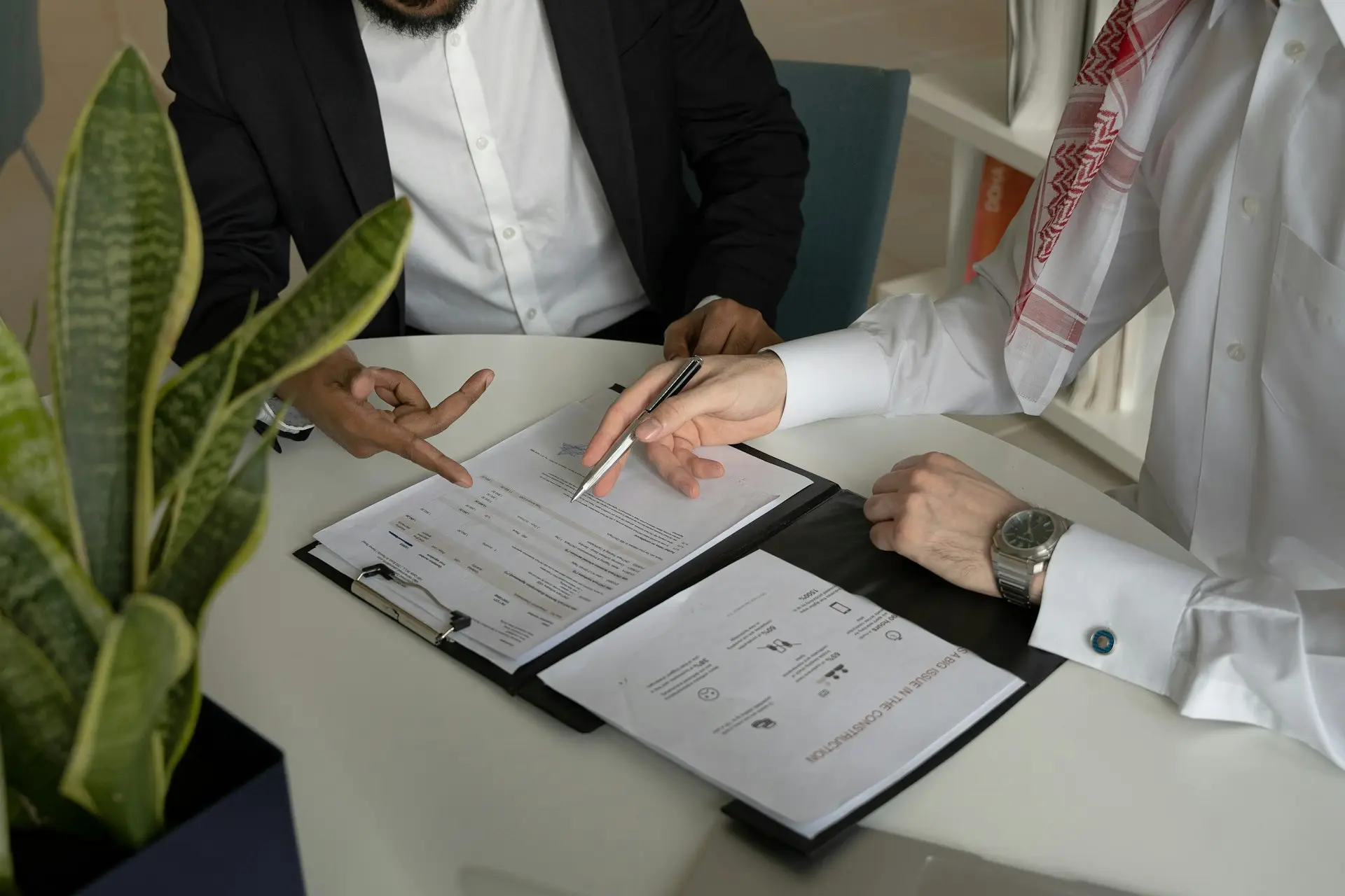 Zwei Männer sitzen mit Papieren und Stift an einem Tisch