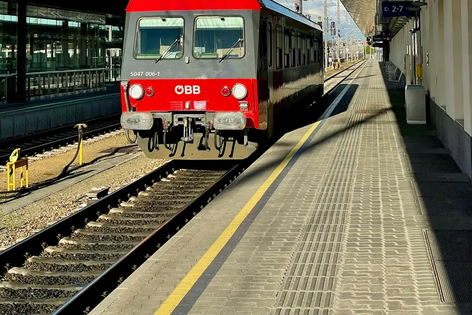 Roter Regionalzug steht an einem Bahnsteig