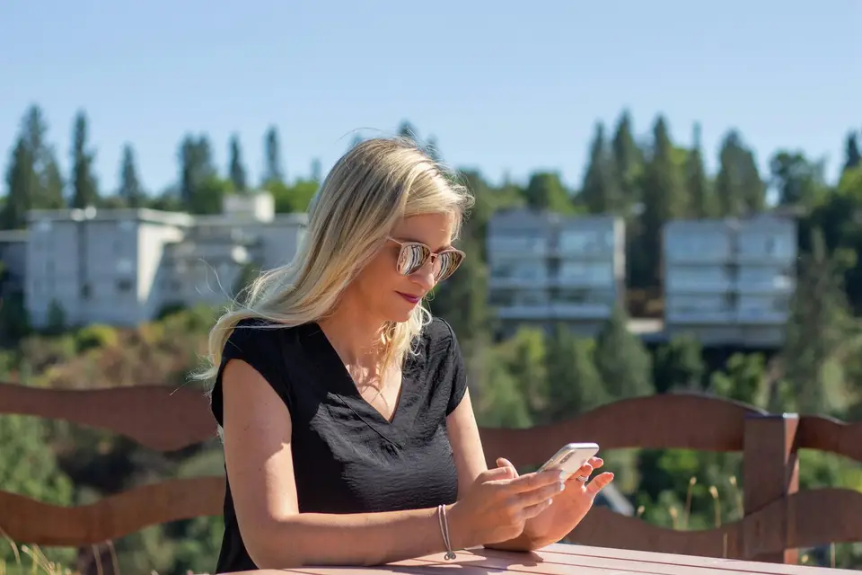 A resident reading on her smartphone at an outdoor table.