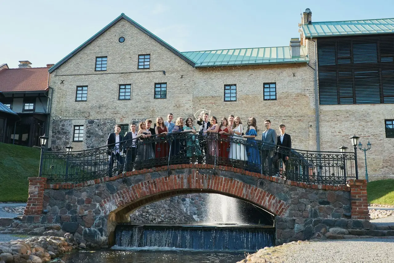A group gathered on a stone bridge in front of a historic building.