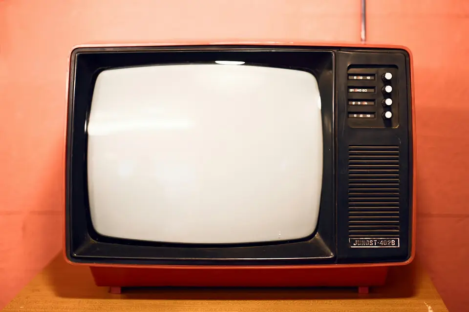 Roter Retro-Fernseher mit leerem Bildschirm vor einer rosa Wand