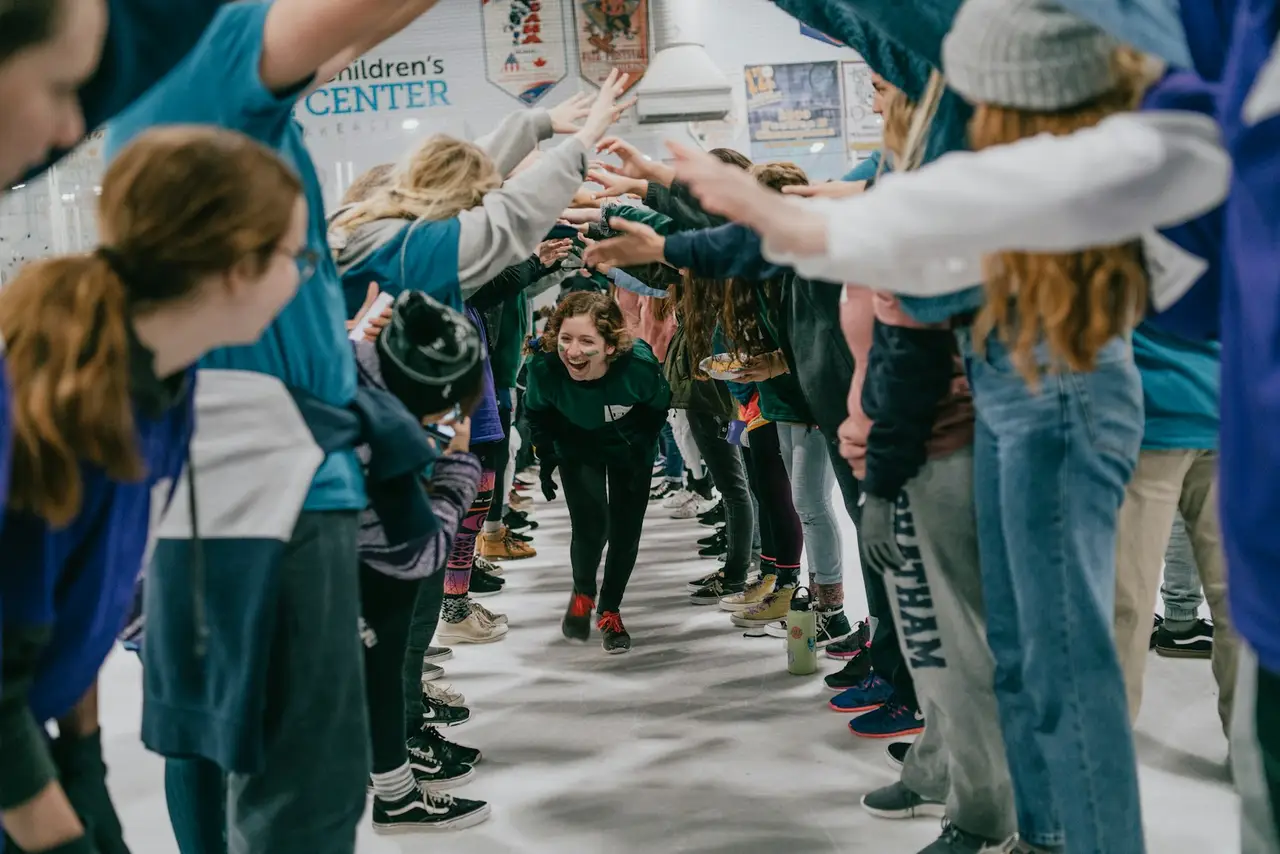 Students running through a cheering tunnel at a school event.