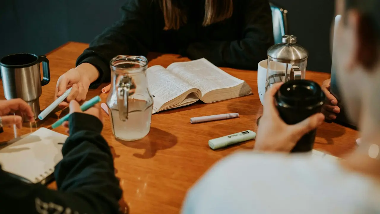 A small group studying together around a table with coffee.