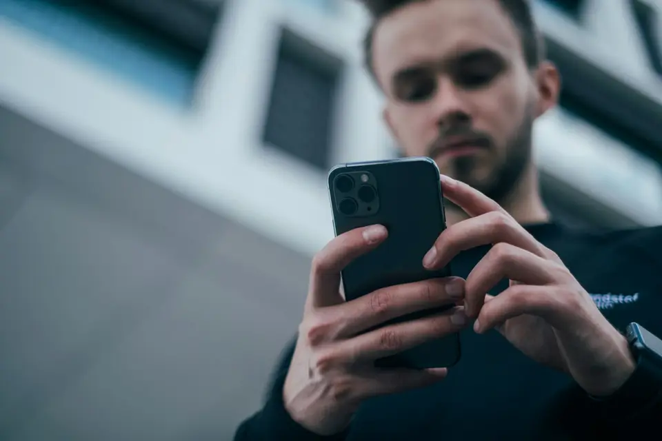 Ein Mann nutzt draußen sein Smartphone.