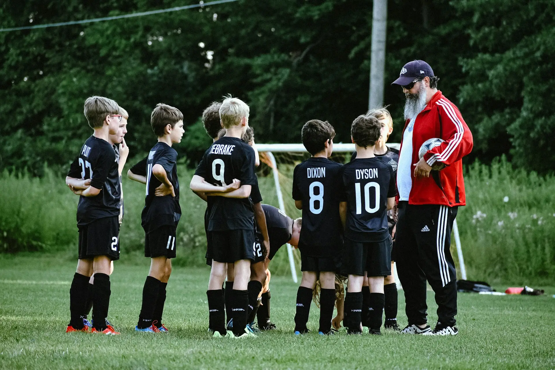 Trainer spricht am Spielfeldrand mit einer Kinder-Fußballmannschaft