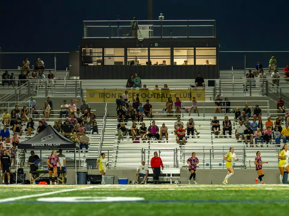 Families watching a game from the stands of a school stadium.